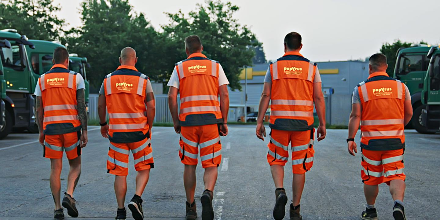 5 Mitarbeiter gehen über ein Firmengelände